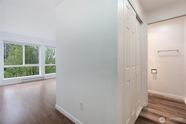 hall with baseboards, a baseboard heating unit, and wood finished floors
