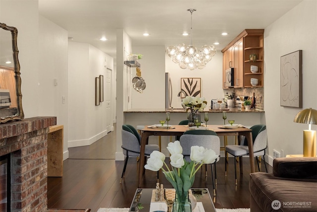 605 5th St Unit B302, Kirkland, WA 98033 - dining room with a brick fireplace, baseboards, dark wood-style floors, a chandelier, and recessed lighting