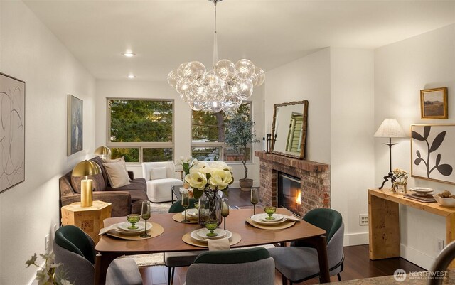 605 5th St Unit B302, Kirkland, WA 98033 - dining space featuring a fireplace, baseboards, an inviting chandelier, and dark wood-type flooring
