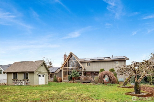 rear view of property with a chimney, roof mounted solar panels, an attached garage, a yard, and a sunroom