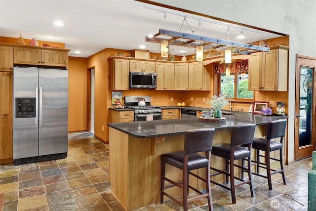 kitchen with dark countertops, a sink, stainless steel appliances, stone finish floor, and recessed lighting