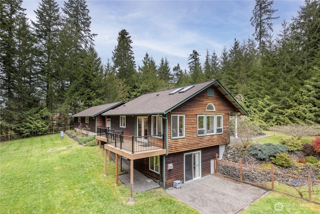 back of property with a wooden deck, a yard, and a patio