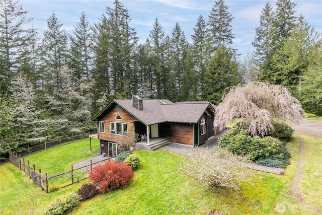 view of front facade featuring a front lawn, driveway, a deck, a shingled roof, and fence