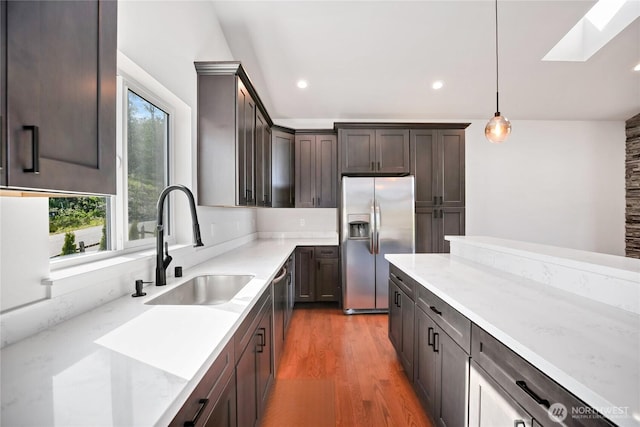 kitchen with dark wood-style flooring, dark brown cabinets, appliances with stainless steel finishes, a sink, and a skylight