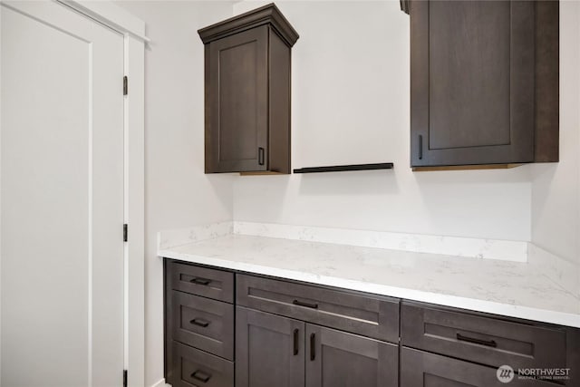 kitchen featuring dark brown cabinets and light stone counters