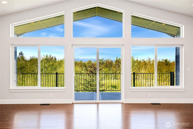 doorway with baseboards, a healthy amount of sunlight, and lofted ceiling