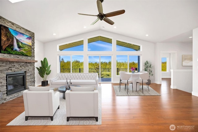 living room with wood finished floors, lofted ceiling, a stone fireplace, ceiling fan, and recessed lighting