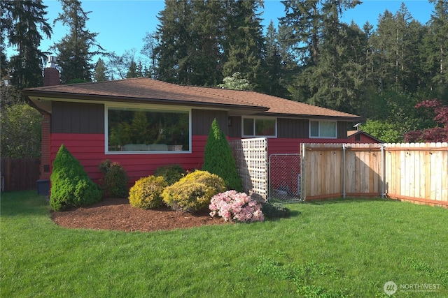 ranch-style home with fence, a chimney, and a front lawn