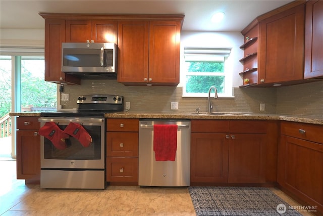 kitchen with brown cabinets, a sink, appliances with stainless steel finishes, and a healthy amount of sunlight