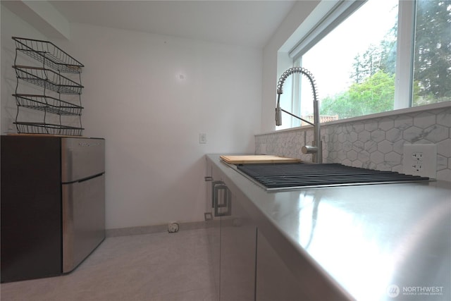 kitchen featuring baseboards, freestanding refrigerator, and backsplash