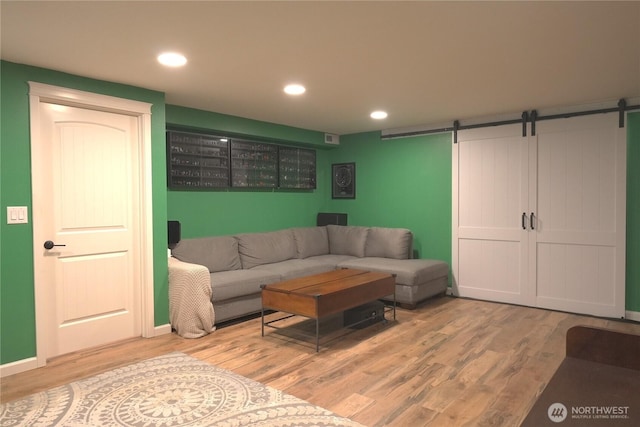 living room featuring a barn door, recessed lighting, and wood finished floors