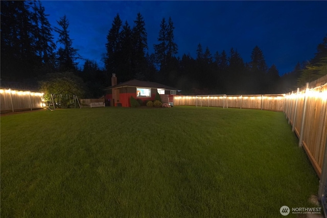 yard at night featuring a fenced backyard