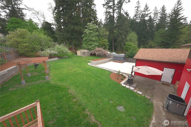view of yard featuring an outdoor structure, a fenced backyard, a patio area, and a storage shed