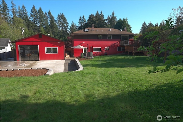 view of yard featuring a detached garage, a deck, and an outbuilding