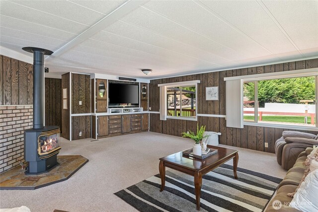 living room featuring a wood stove, wooden walls, and carpet
