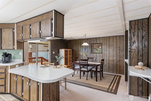 kitchen featuring wood walls, light carpet, and light countertops
