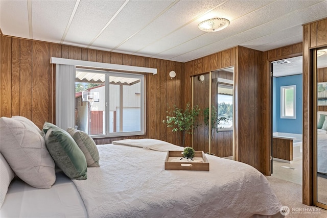 bedroom with light carpet, wooden walls, and multiple windows