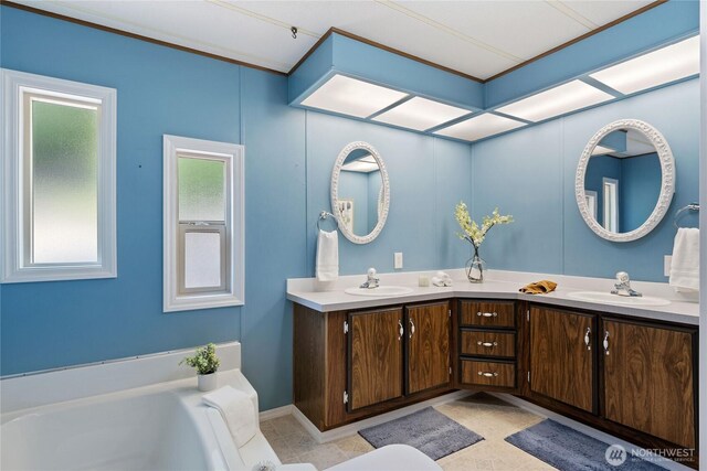 bathroom with a bath, double vanity, a sink, and tile patterned floors