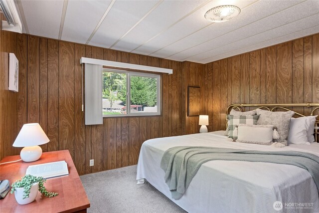 carpeted bedroom featuring wood walls