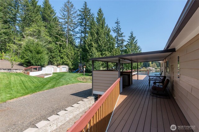 wooden terrace with a lawn, a storage unit, an outdoor structure, and a playground