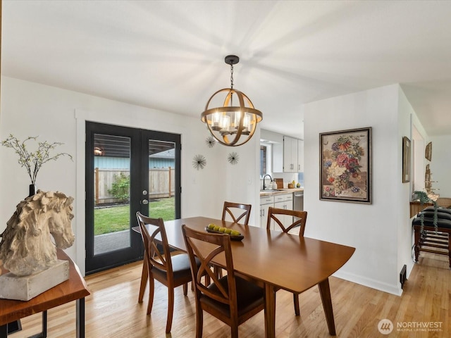 dining area with a chandelier, french doors, and light wood-style flooring