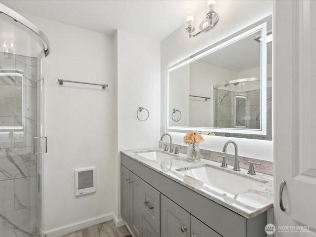 full bathroom featuring a stall shower, double vanity, heating unit, and wood finished floors