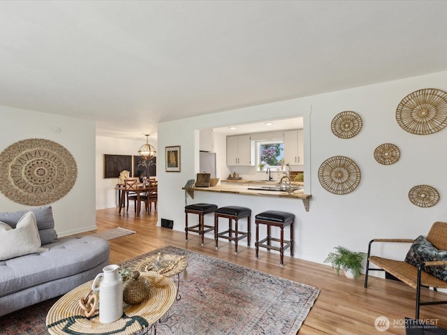 living area featuring light wood-type flooring and a chandelier