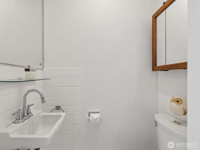 half bathroom with a sink, toilet, and tile walls