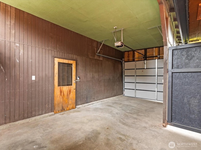 garage featuring a garage door opener and wooden walls