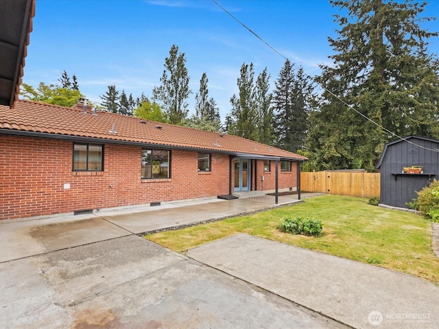 back of property with a tile roof, a patio, a shed, and an outbuilding