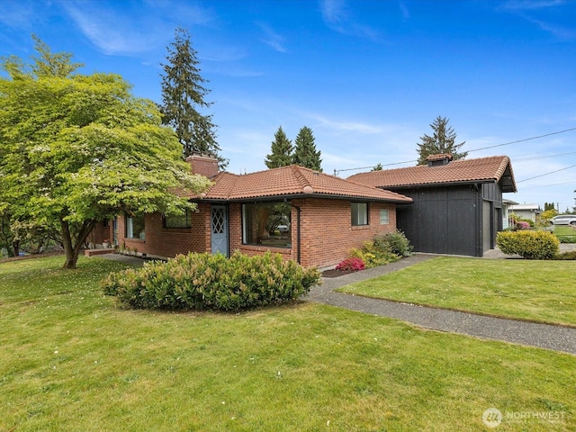 single story home featuring a chimney, a tile roof, a front yard, and brick siding