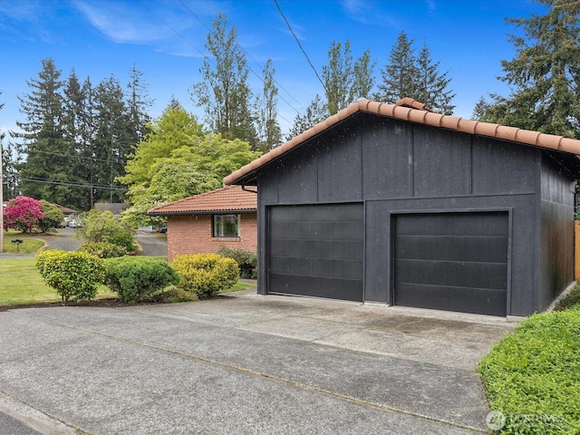 view of side of property with a tile roof and a detached garage