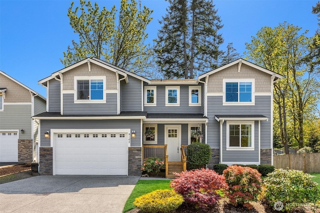 craftsman-style home featuring a garage, fence, concrete driveway, and stone siding