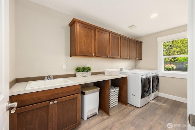 washroom with cabinet space, a sink, light wood-style flooring, visible vents, and washing machine and dryer