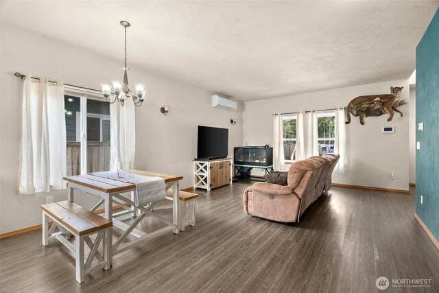 living area featuring baseboards, an inviting chandelier, dark wood-style floors, and a wall unit AC