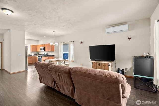 living area with a wall mounted air conditioner, dark wood finished floors, baseboards, and a chandelier