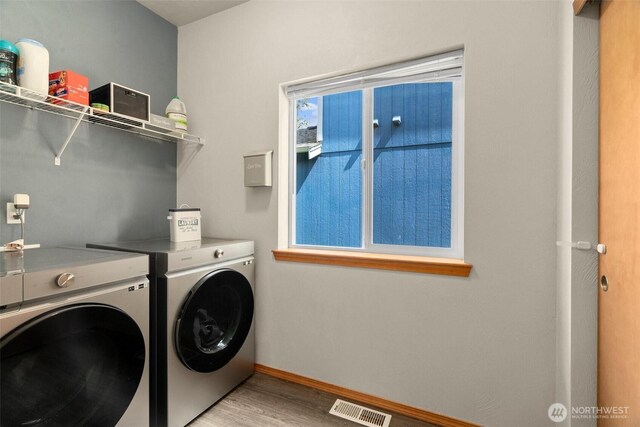 laundry room with light wood finished floors, washing machine and dryer, baseboards, visible vents, and laundry area