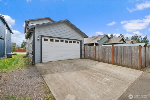 exterior space with central AC unit, fence, and driveway