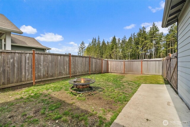 view of yard with a fenced backyard, a patio area, and an outdoor fire pit