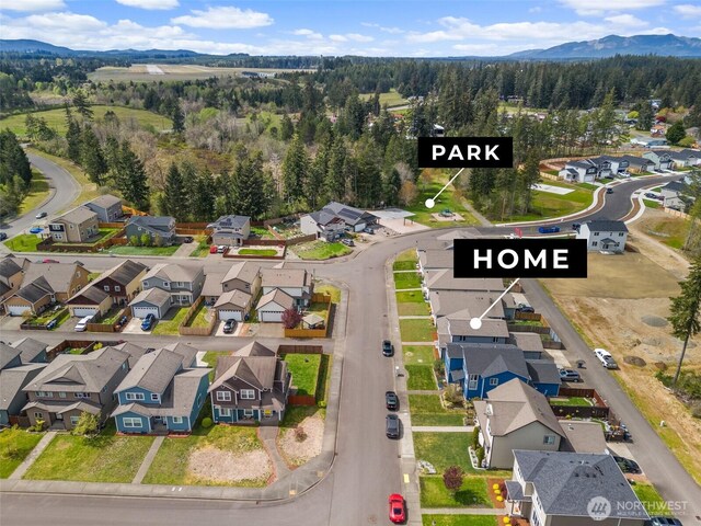 drone / aerial view featuring a mountain view, a view of trees, and a residential view