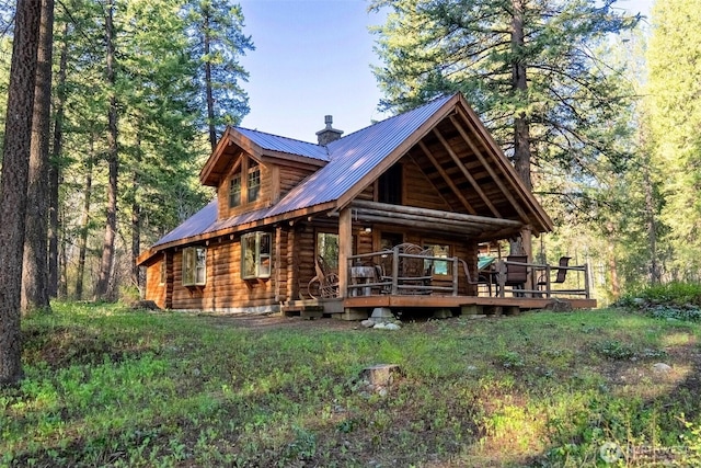 rear view of house with a chimney, metal roof, a wooden deck, and log exterior
