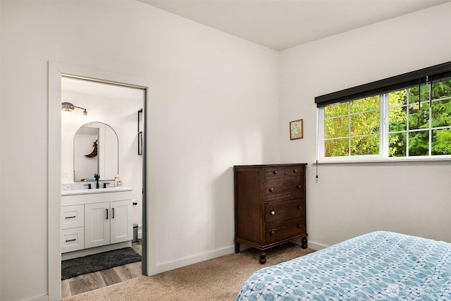 carpeted bedroom with baseboards, a sink, and ensuite bathroom