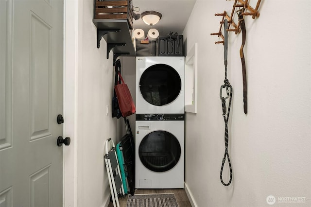 washroom featuring baseboards, stacked washing maching and dryer, and laundry area