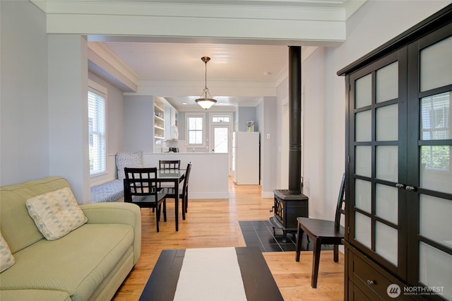 living room featuring ornamental molding, wood finished floors, and a wood stove
