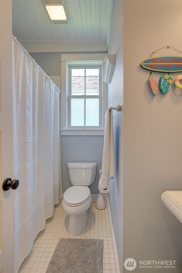 bathroom featuring toilet, ornamental molding, tile patterned floors, a shower with curtain, and baseboards