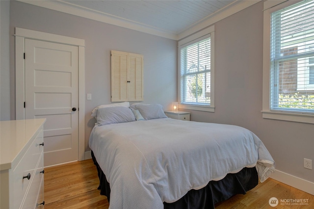 bedroom with multiple windows, light wood finished floors, ornamental molding, and baseboards