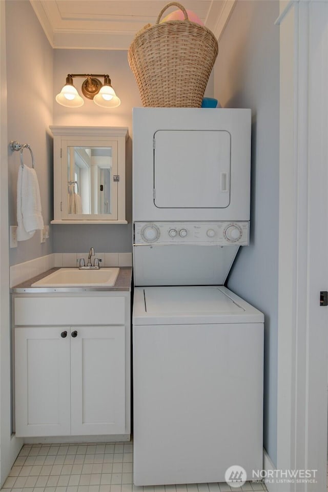 clothes washing area featuring stacked washer / drying machine, cabinet space, and crown molding