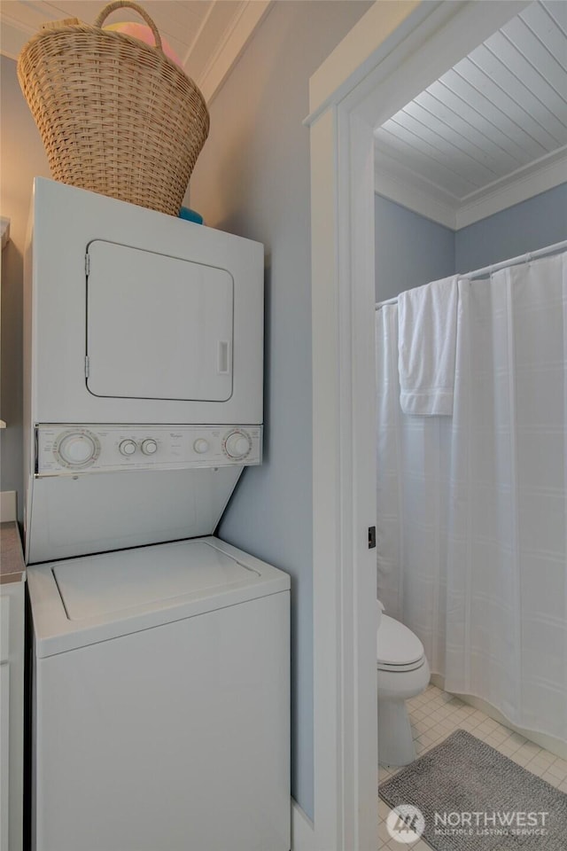 clothes washing area featuring stacked washer / drying machine, tile patterned floors, and ornamental molding