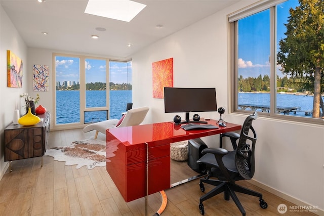 office with a wealth of natural light, hardwood / wood-style floors, baseboards, and a skylight