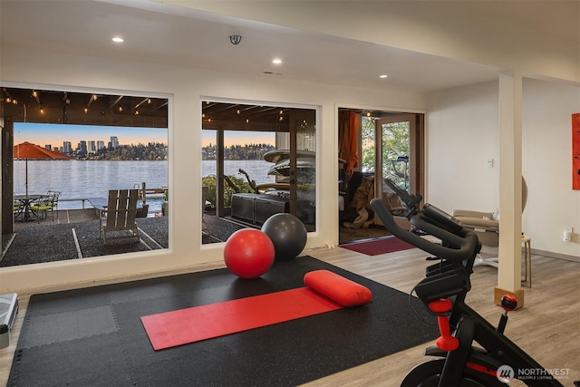 exercise room featuring recessed lighting, wood finished floors, and a water view